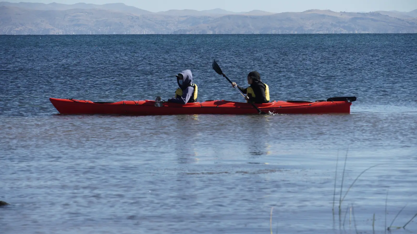 Red kayak with two people paddling on Lake Titicaca