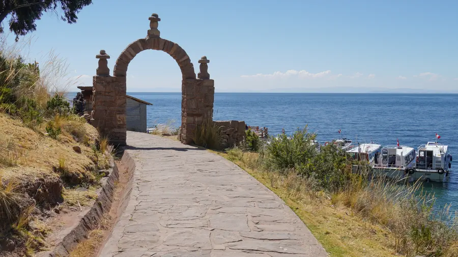 Stone arch on the Taquile island path, with the lake and boats behind